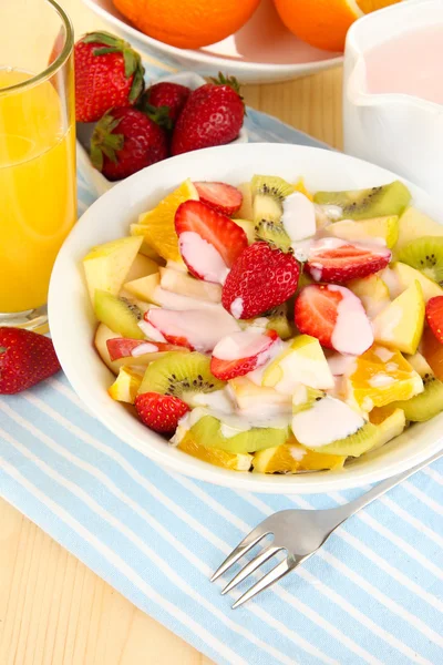 Useful fruit salad of fresh fruits and berries in bowl on napkin on wooden table close-up — Stock Photo, Image