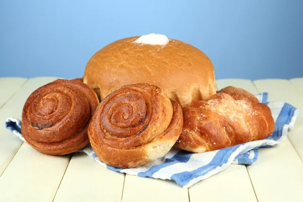 Composition with bread, rolls and napkin on wooden table, on color background — Stock Photo, Image