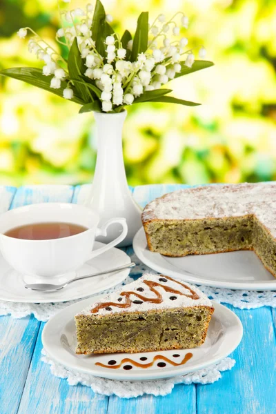 Delicious poppy seed cake with cup of tea on table on bright background — Stock Photo, Image