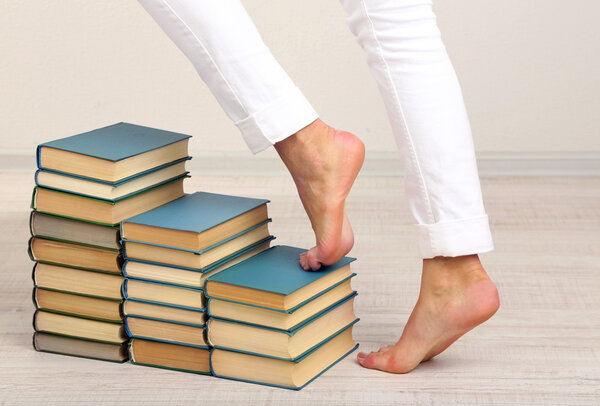 Girl climbs up on pile of books