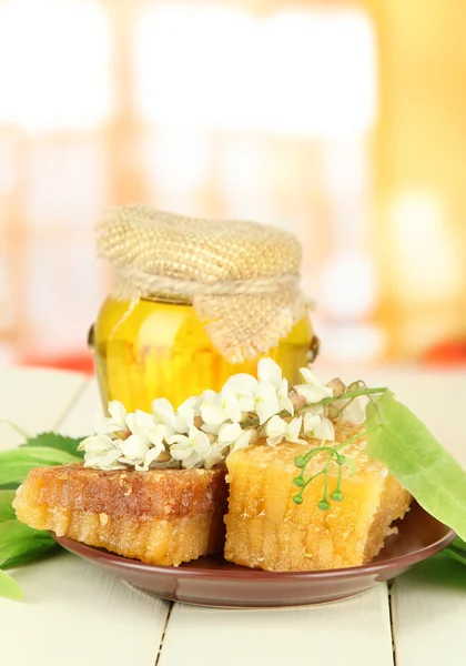 Vaso di miele con fiori di tiglio, acacia su tavolo di legno a colori su sfondo brillante — Foto Stock