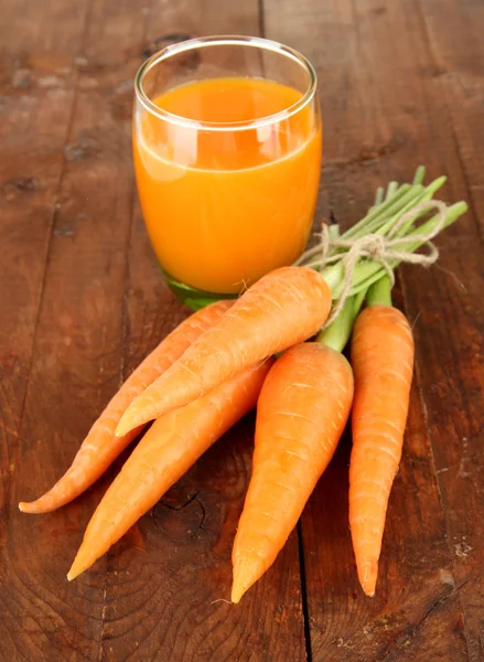 Montón de zanahorias, vaso de jugo, sobre fondo de madera —  Fotos de Stock