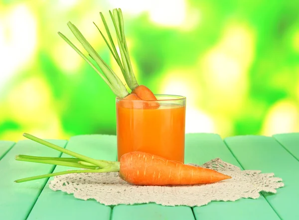 Vidro de suco de cenoura, na mesa de madeira a cores no fundo brilhante — Fotografia de Stock