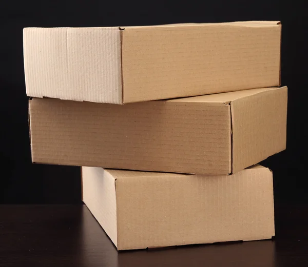 Parcels boxes on wooden table, on black background — Stock Photo, Image