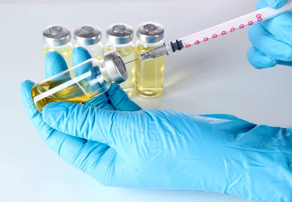 Medical bottles and syringe in hand on gray background — Stock Photo, Image