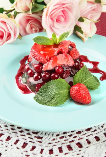 Sabroso postre de gelatina con bayas frescas, sobre fondo de rosas rosadas —  Fotos de Stock