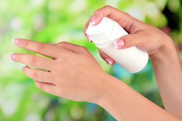 Woman applying cream on hands on bright background — Stock Photo, Image