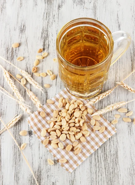 Bier in glas en noten op servet op houten tafel — Stockfoto