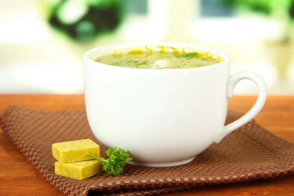 Tasse Suppe mit Brühwürfeln auf Holztisch — Stockfoto
