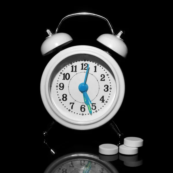 Relógio de alarme de estilo antigo e pílulas, isolado em preto — Fotografia de Stock