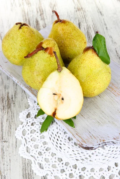 Pears on board on napkin on wooden background — Stock Photo, Image