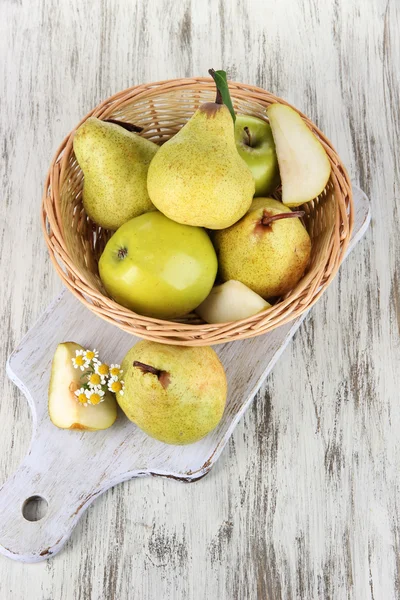 Pears in basket on board on wooden table — Stock Photo, Image