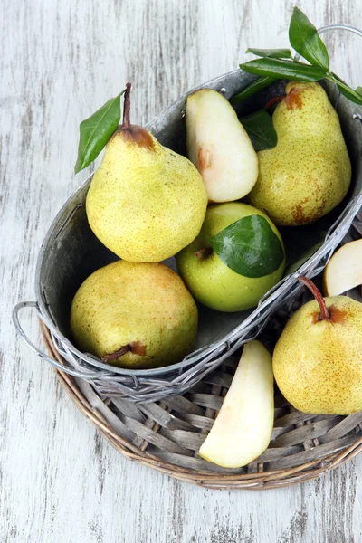 Pears in basket on braided tray on wooden table — Stock Photo, Image