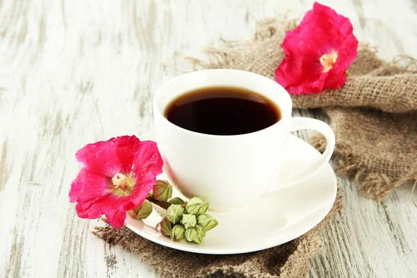 Xícara de café e flores de malva rosa em fundo de madeira — Fotografia de Stock