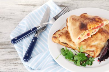 Pizza calzones tabakta üzerine peçete ahşap masa üzerinde
