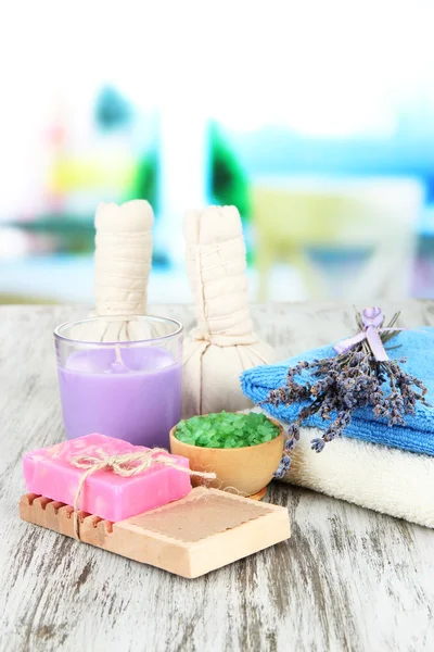 Stillleben mit Lavendelkerze, Seife, Massagekugeln, Flaschen, Seife und frischem Lavendel, auf Holztisch vor hellem Hintergrund — Stockfoto