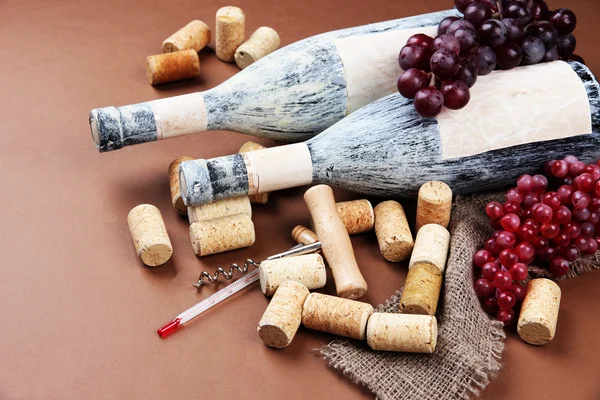 Old bottles of wine, grapes and corks on brown background — Stock Photo, Image