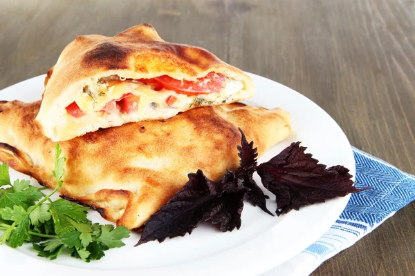 Pizza calzone on plate on napkin on wooden table — Stock Photo, Image