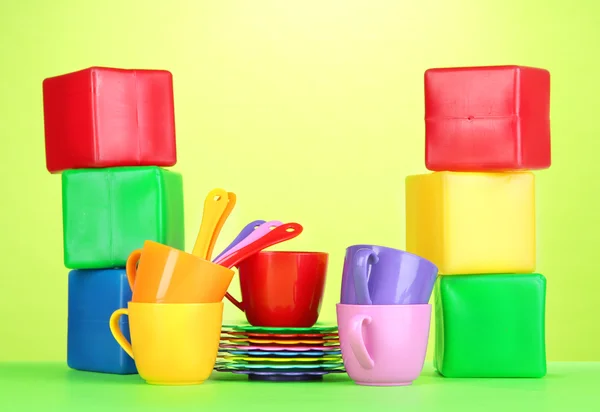 Set of children's dishes and cubes on light green background — Stock Photo, Image