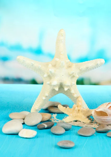 White starfishes on blue wooden table on sea background — Stock Photo, Image