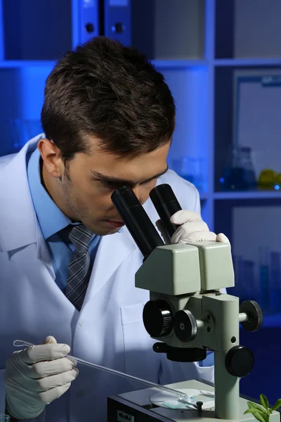 Científico de laboratorio joven mirando el microscopio en el laboratorio — Foto de Stock