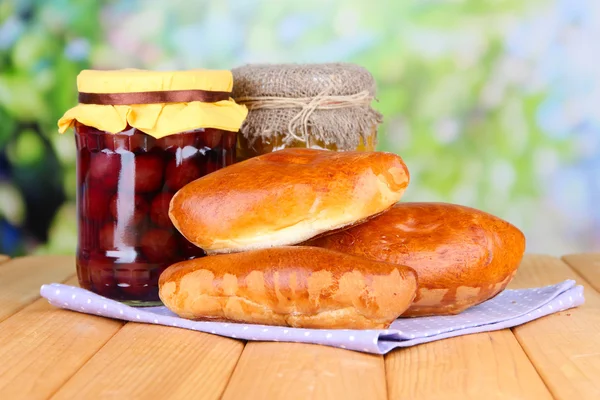 Vers gebakken pasteitjes met fruit jam, op houten tafel, op lichte achtergrond — Stockfoto