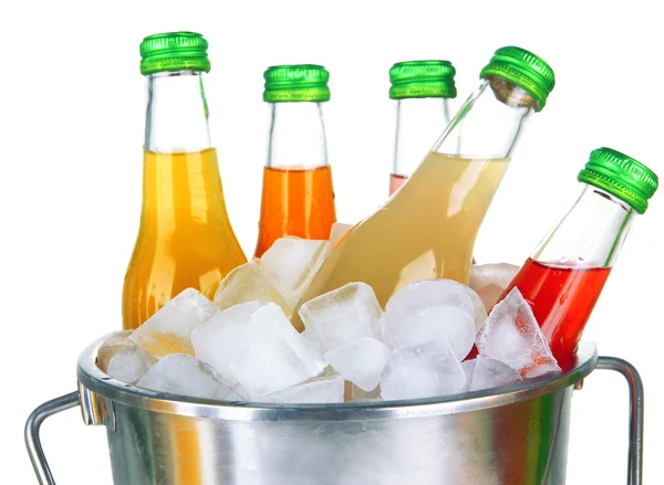 Бутылки с вкусными напитками в ведре с кубиками льда, изолированные на белом — стоковое фото