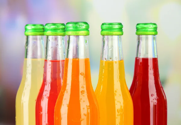 Bottiglie con gustose bevande su sfondo luminoso — Foto Stock