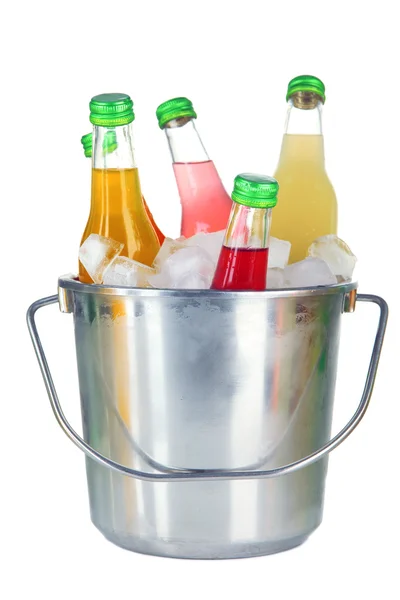 Bottles with tasty drinks in bucket with ice cubes, isolated on white — Stock Photo, Image