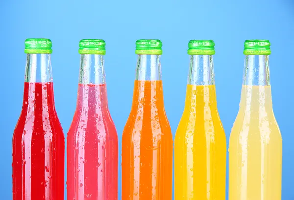 Botellas con bebidas sabrosas sobre fondo brillante — Foto de Stock