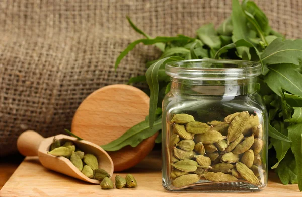 Jar of green cardamom with rocket on canvas background close-up — Stock Photo, Image