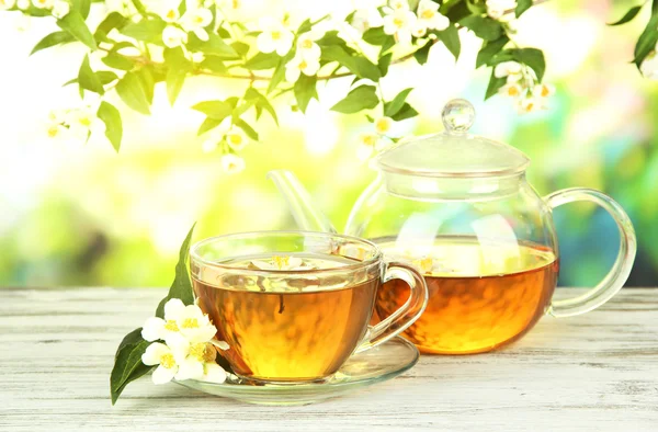 Taza de té con jazmín, sobre mesa de madera, sobre fondo brillante — Foto de Stock