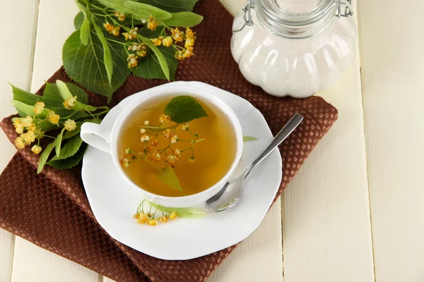 Kopje thee met linden op servet op houten tafel — Stockfoto