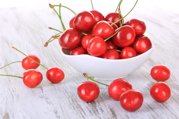 Cherry berries in bowl on wooden table close up — Stock Photo, Image