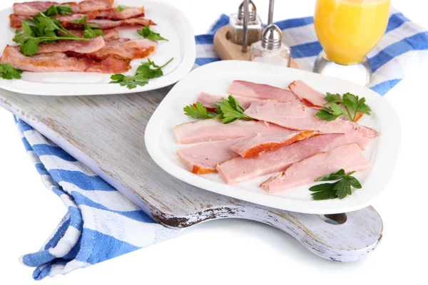 Bacon on plates on napkin on board isolated on white — Stock Photo, Image