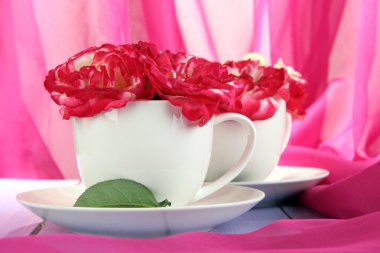 gül pembe kumaş zemin üzerine ahşap masa üstünde CUPS