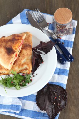 Pizza calzones tabakta üzerine peçete ahşap masa üzerinde