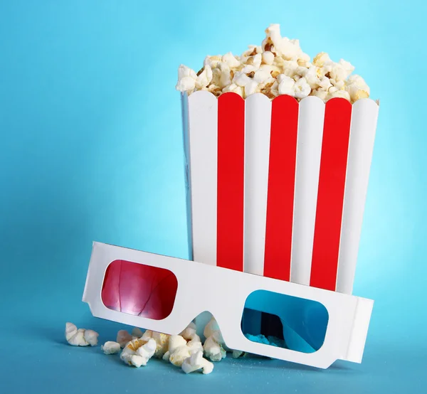 Popcorn e occhiali 3D su sfondo blu — Foto Stock