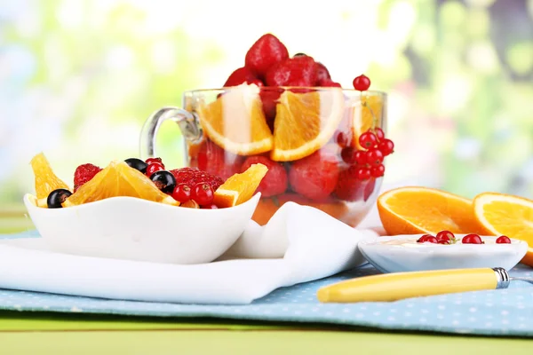 Ensalada de frutas útil en taza de vidrio y tazón en mesa de madera sobre fondo natural —  Fotos de Stock