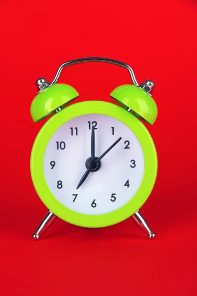 Green alarm clock on red background — Stock Photo, Image