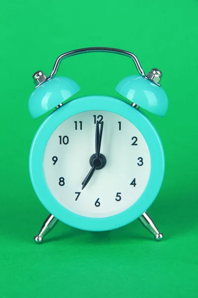 Reloj despertador azul sobre fondo verde — Foto de Stock