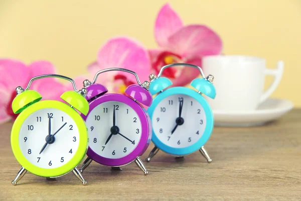 Relógio de alarme colorido na mesa no fundo bege — Fotografia de Stock