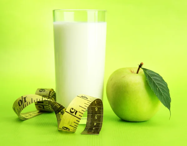 Glas van kefir, apple en meetlint, op groene achtergrond — Stockfoto