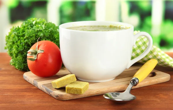 Cup of soup with bouillon cubes on wooden table — Stock Photo, Image