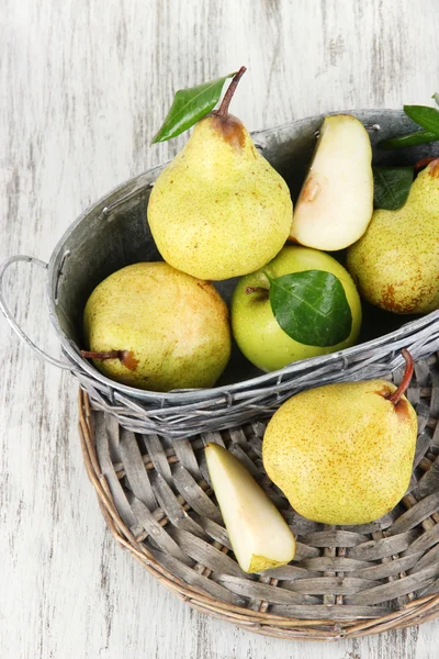 Pears in basket on braided tray on wooden table — Stock Photo, Image