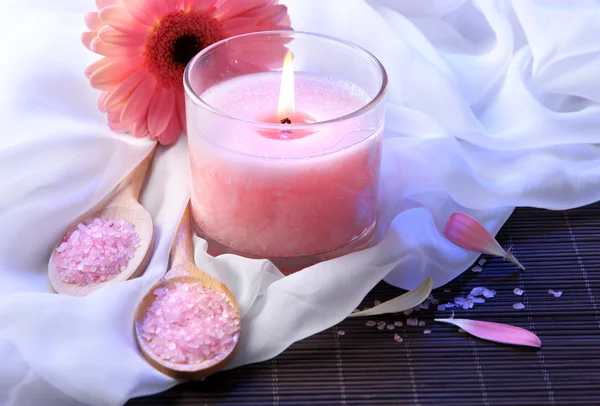 Красивая розовая свеча с цветами на бамбуковом коврике — стоковое фото