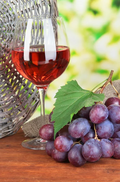 Zralé vynikající hrozny se sklenicí vína na stole na světlé pozadí — Stock fotografie