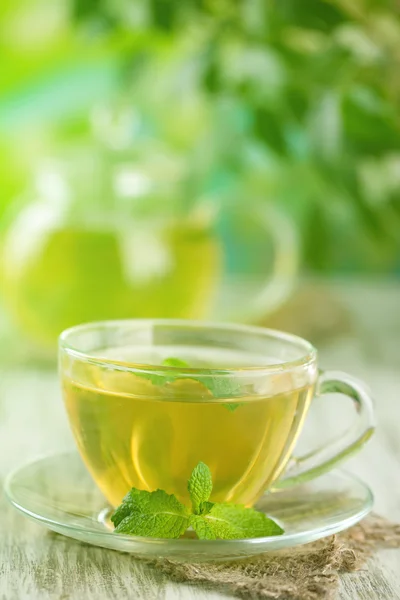 Tazza di tisana con fiori di menta freschi sul tavolo di legno — Foto Stock