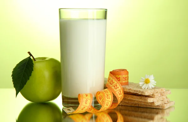 Glas Kefir, Apfel, Knäckebrot und Maßband, auf grünem Hintergrund — Stockfoto