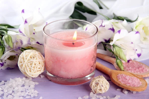 Beautiful pink candle with flowers on purple wooden background — Stock Photo, Image